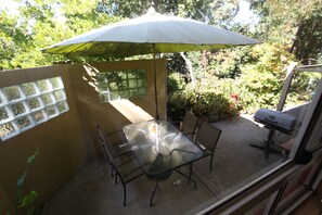 A patio with a glass table and chairs, an umbrella, and a grill. - Amble at Hahndorf (Hahndorf)