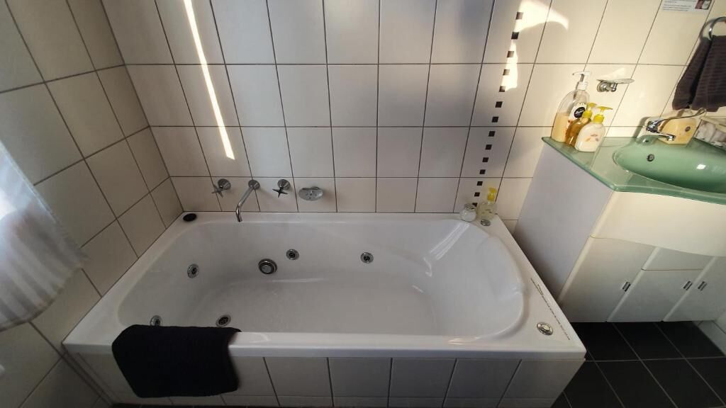 Ein modernes Badezimmer mit einer freistehenden Badewanne, einem Glastischwaschbecken und einem Spiegel.