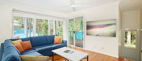 A modern living room with a blue sofa, a white coffee table, and a ceiling fan.