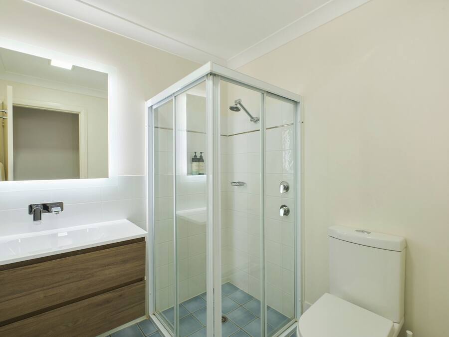 A modern bathroom with a glass-enclosed shower, a white sink, and a toilet.
