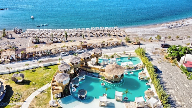 Un resort con piscina, sillas de descanso frente a la playa y vistas a la costa.