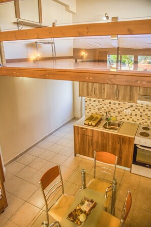 Una cocina moderna con armarios de madera, salpicadero de azulejos y una zona de comedor con mesa y sillas.