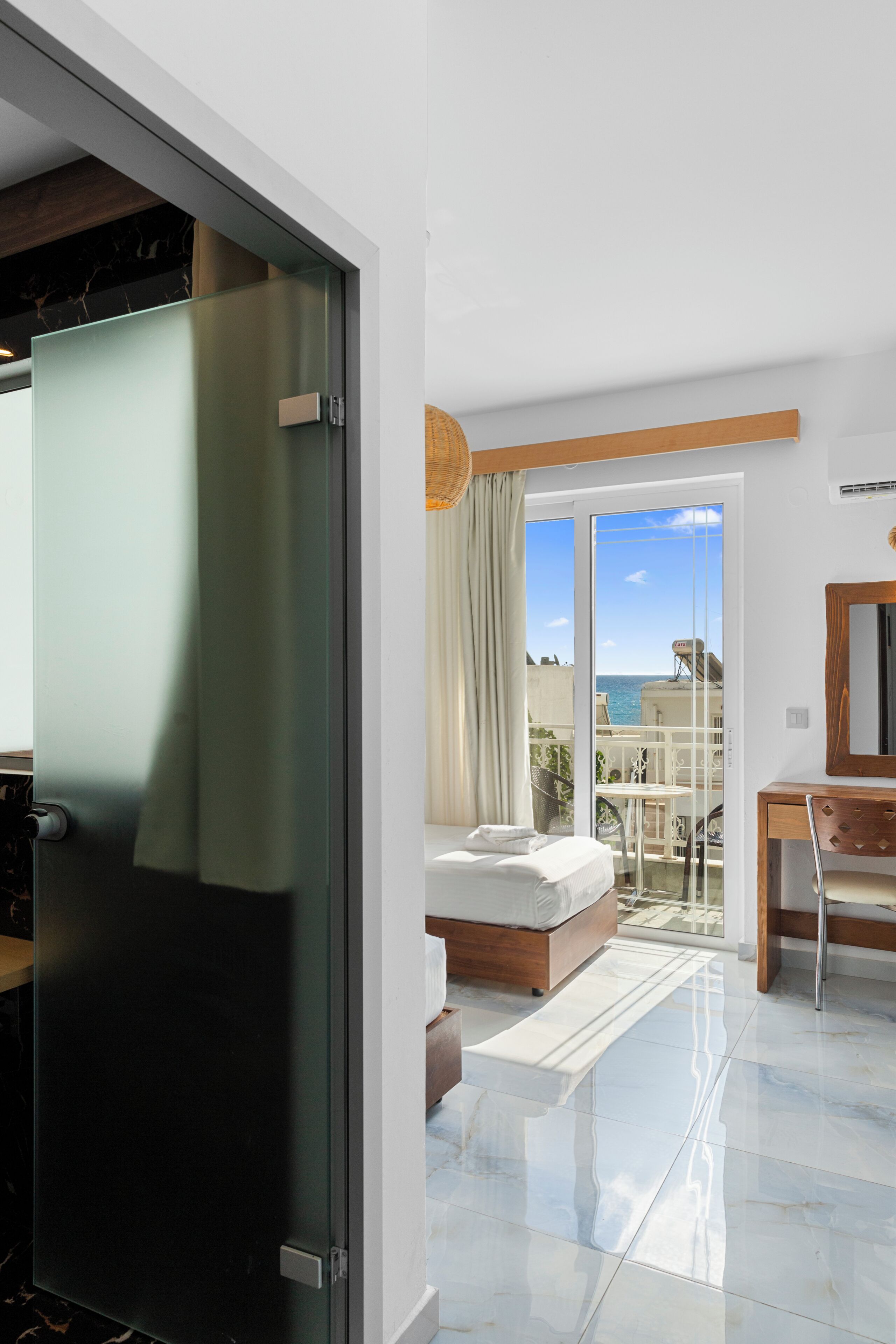 Ein modernes Hotelzimmer mit Bett, Schreibtisch und Blick aufs Meer.