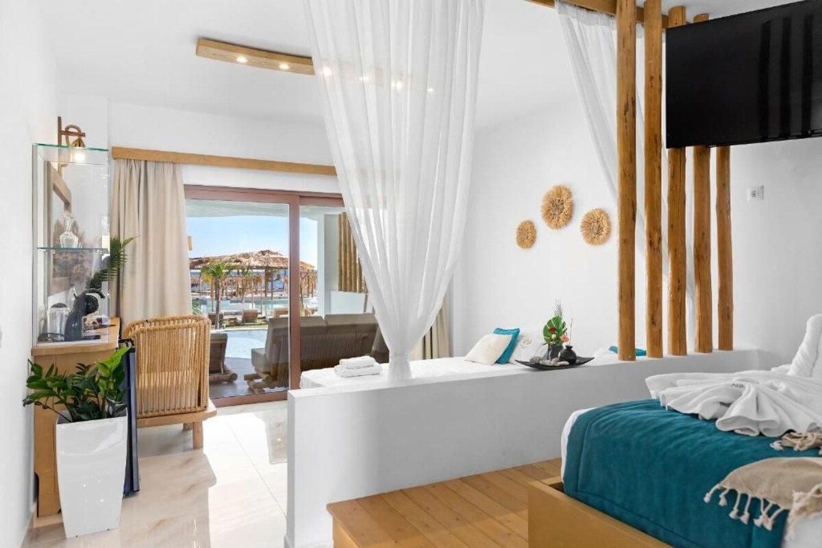 A modern hotel room with a bed, a desk, a chair, and a view of the pool area.