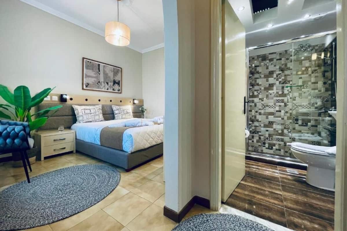 Un dormitorio moderno con una cama, mesitas de noche y una planta grande en maceta.