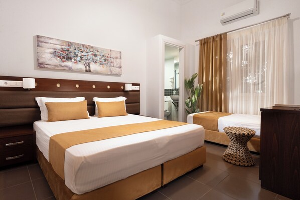 A modern hotel room with a large bed, a smaller bed, a bedside table, and a painting on the wall.