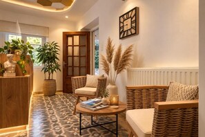 A cozy living area with wicker furniture, a round coffee table, and decorative plants. - Semiramis Hotel (Milos)