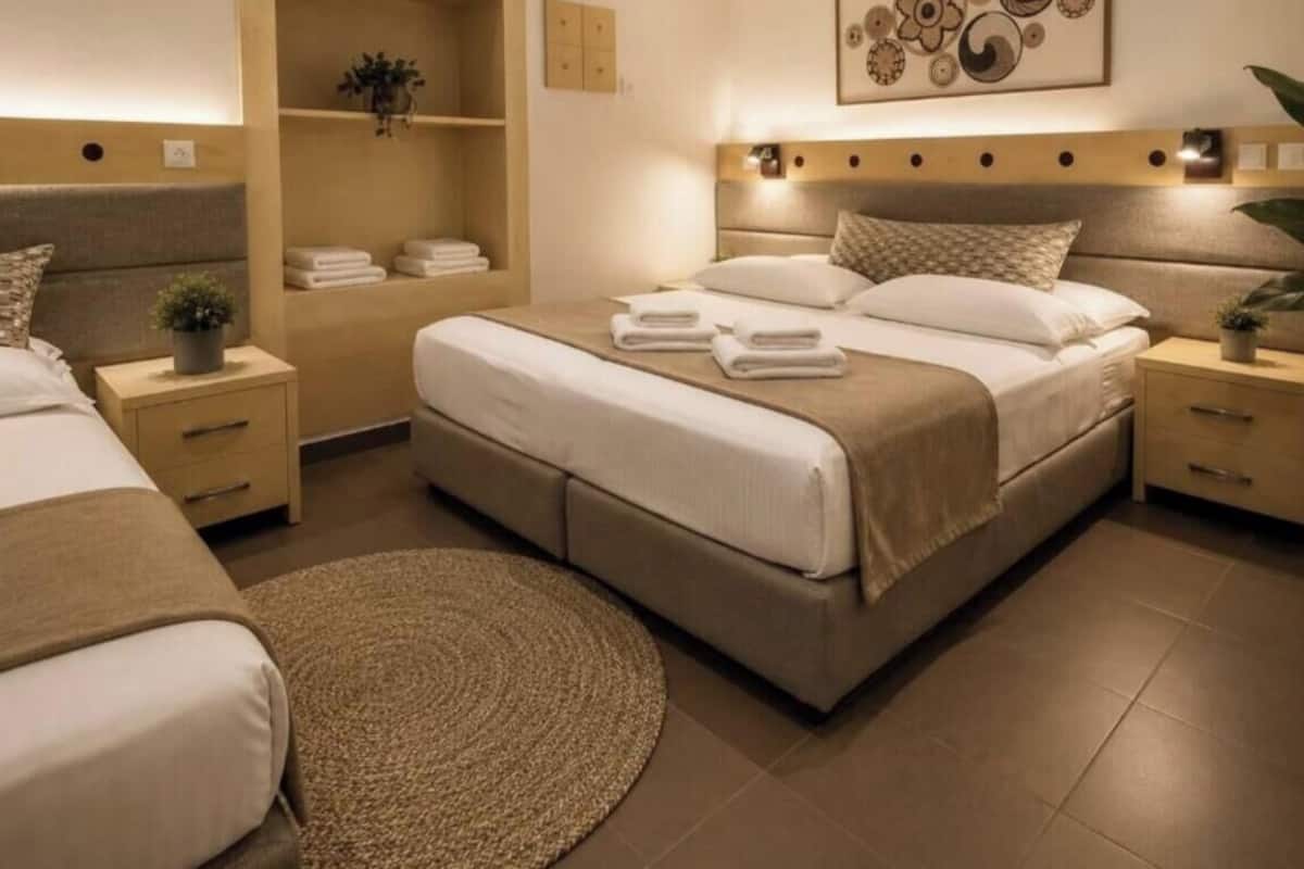 Una habitación de hotel con una cama grande, dos mesitas de noche, un tapete redondo y una obra de arte colgada en la pared.
