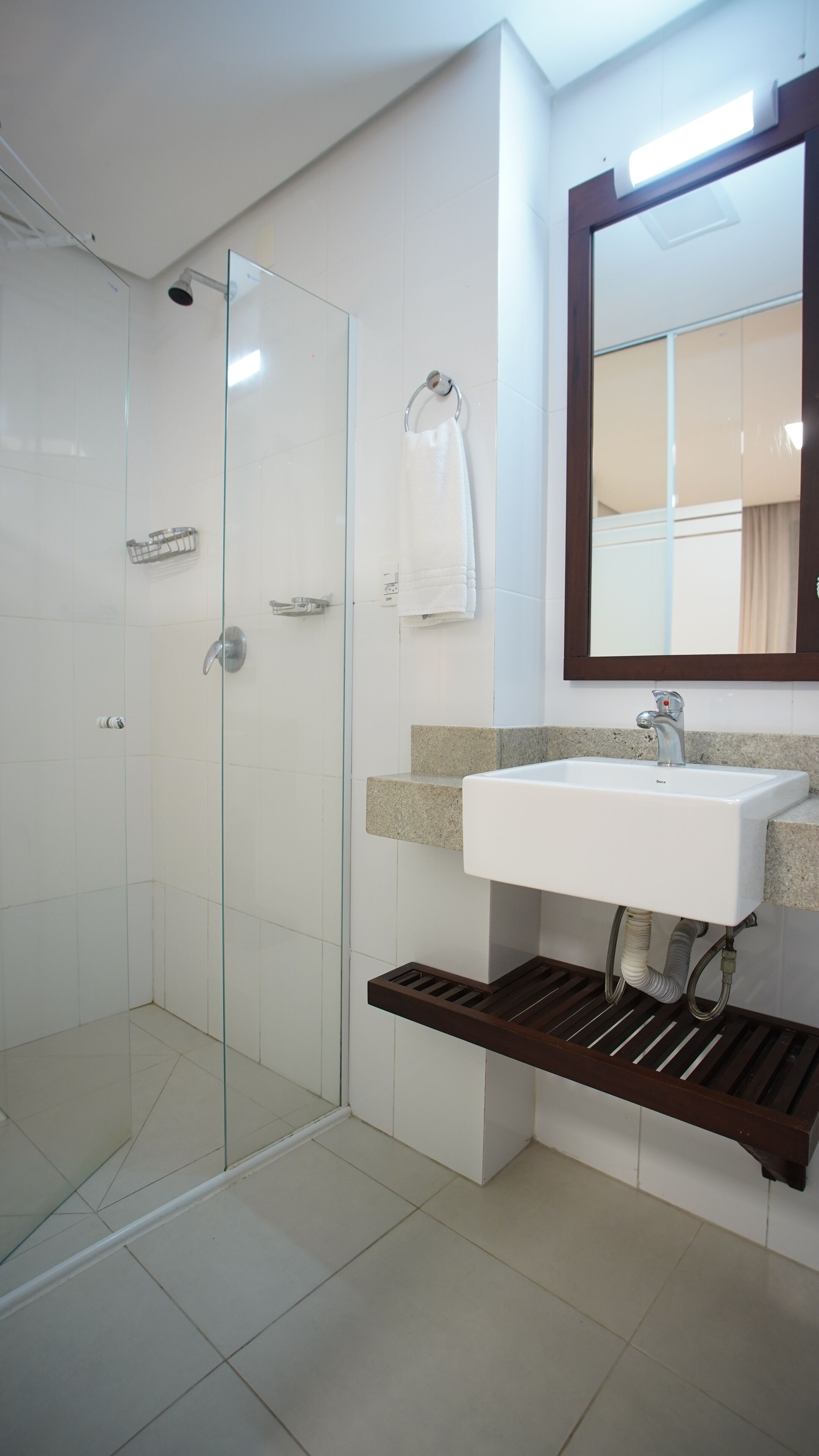 A modern bathroom with a glass-enclosed shower, a white sink, and a mirror above the sink.