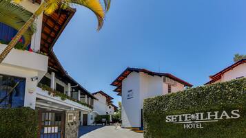 A hotel entrance with a gated driveway, palm trees, and a clear blue sky.