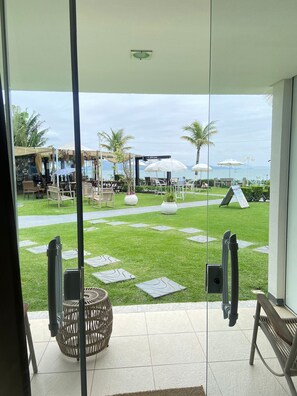 Enjoy a tranquil retreat with a glass door leading to an outdoor space featuring a lawn, wicker chairs, and a dining area.