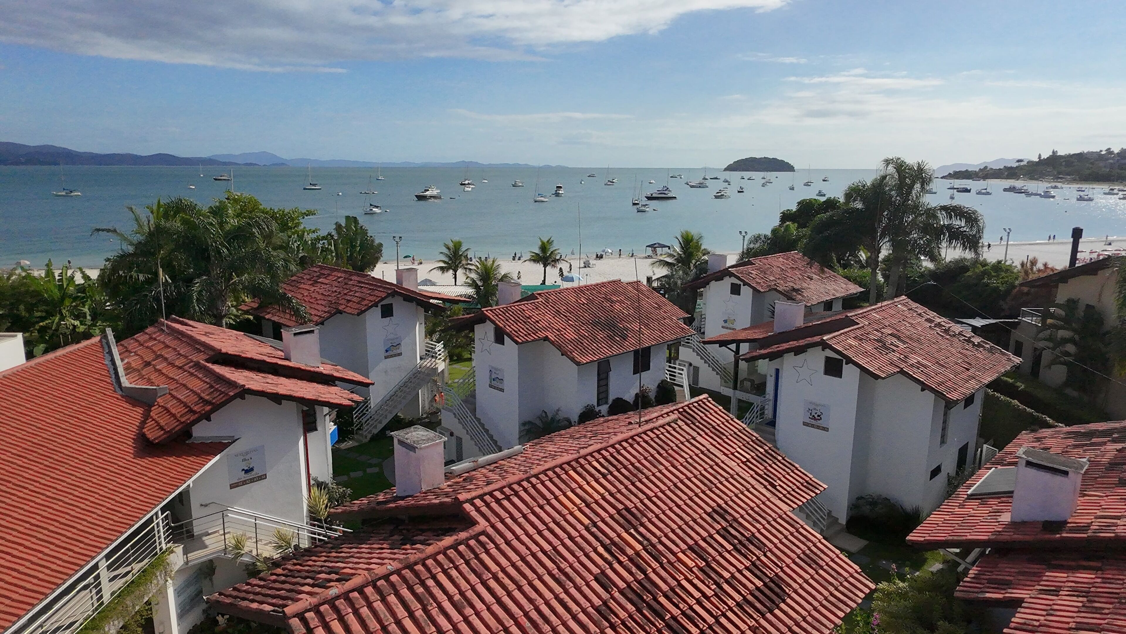 Un village côtier doté d’une architecture traditionnelle, d’une plage et de bateaux amarrés dans l’eau.