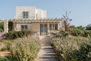 Un bâtiment doté d’une façade en pierre, d’une pergola en bois et d’un chemin menant à l’entrée.