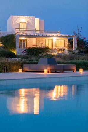 A modern villa with a pool, stone facade, and outdoor seating area. - Stagones Luxury Villas (Paros)