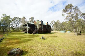 A wooden cabin with a covered porch and a staircase leading to an upper level. - Manzanilla Ridge (Lovedale)