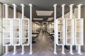 A spacious library with white shelving units and tables, featuring books and decorative items. - Lo Scoiattolo (Pralormo)