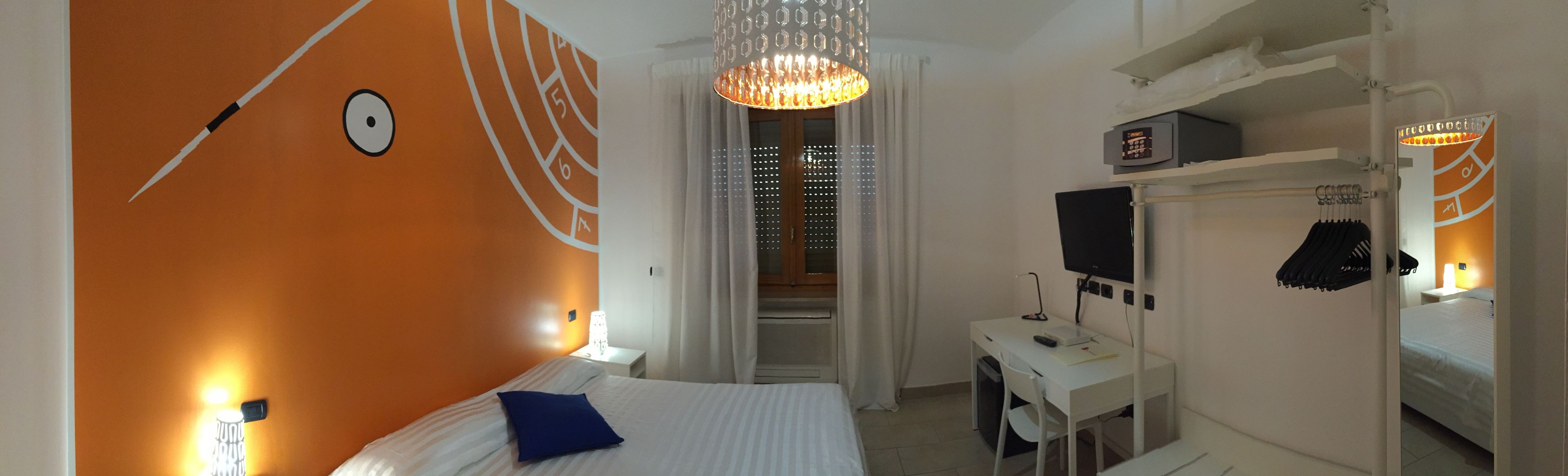 Une chambre d’hôtel avec un lit, un bureau, un ordinateur et un miroir.