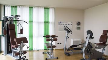 A gym with various exercise equipment including a bench press, a leg press, and an elliptical machine.