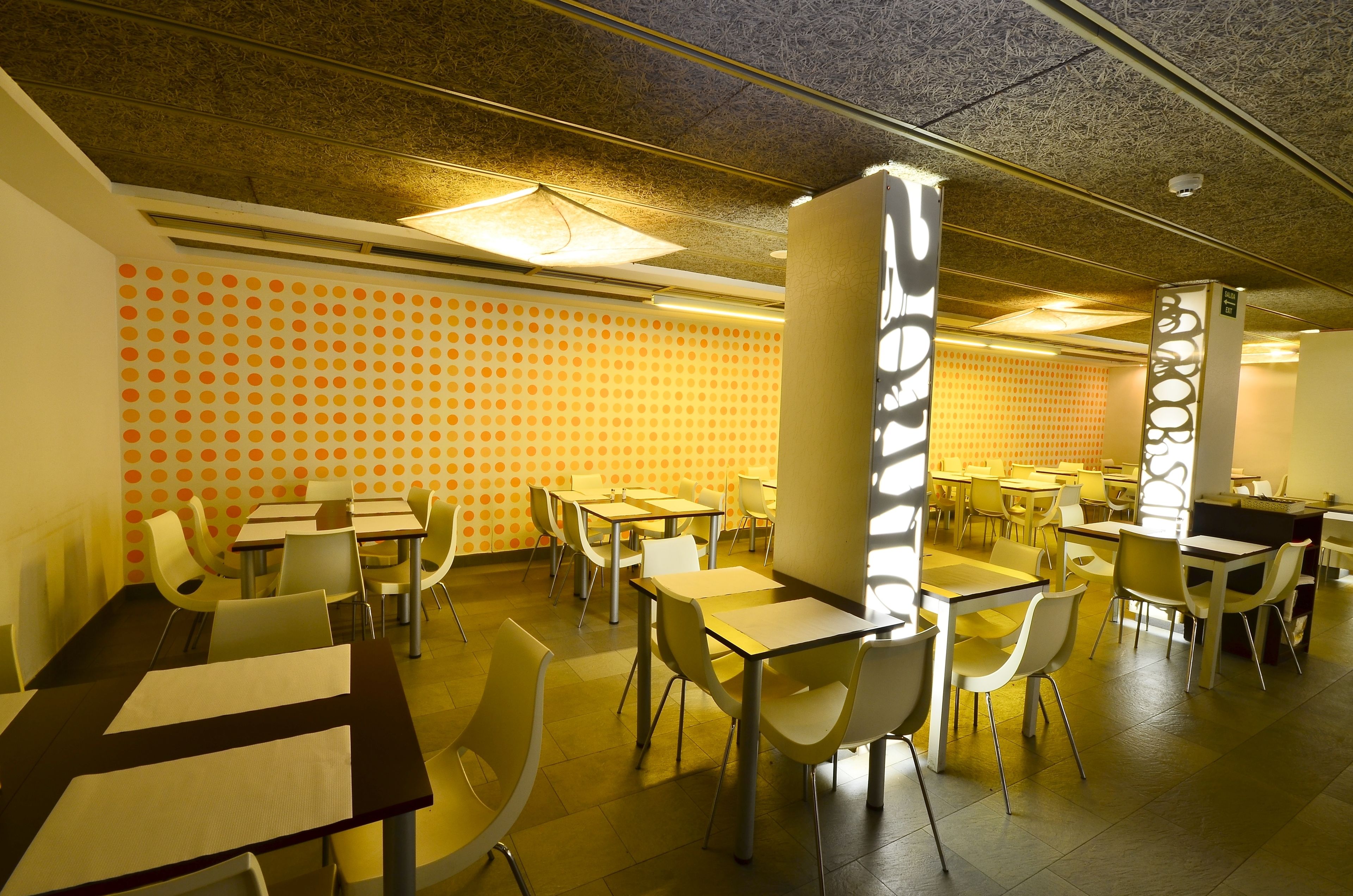 Un comedor con mesas y sillas, un pared con diseño y un techo con textura.