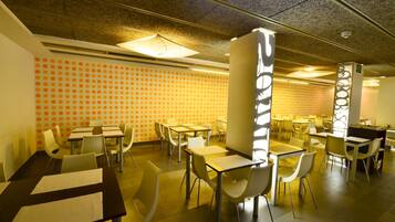 Un comedor con mesas y sillas, un pared con diseño y un techo con textura.