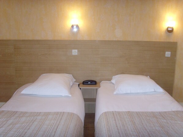 A hotel room with two single beds, a wooden headboard, and two wall-mounted lights. - Hotel de Rennes (Le Mans)