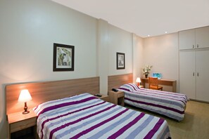 A hotel room with two beds, a desk, a chair, a lamp, and a wardrobe. - Hotel Inglês (Rio de Janeiro)