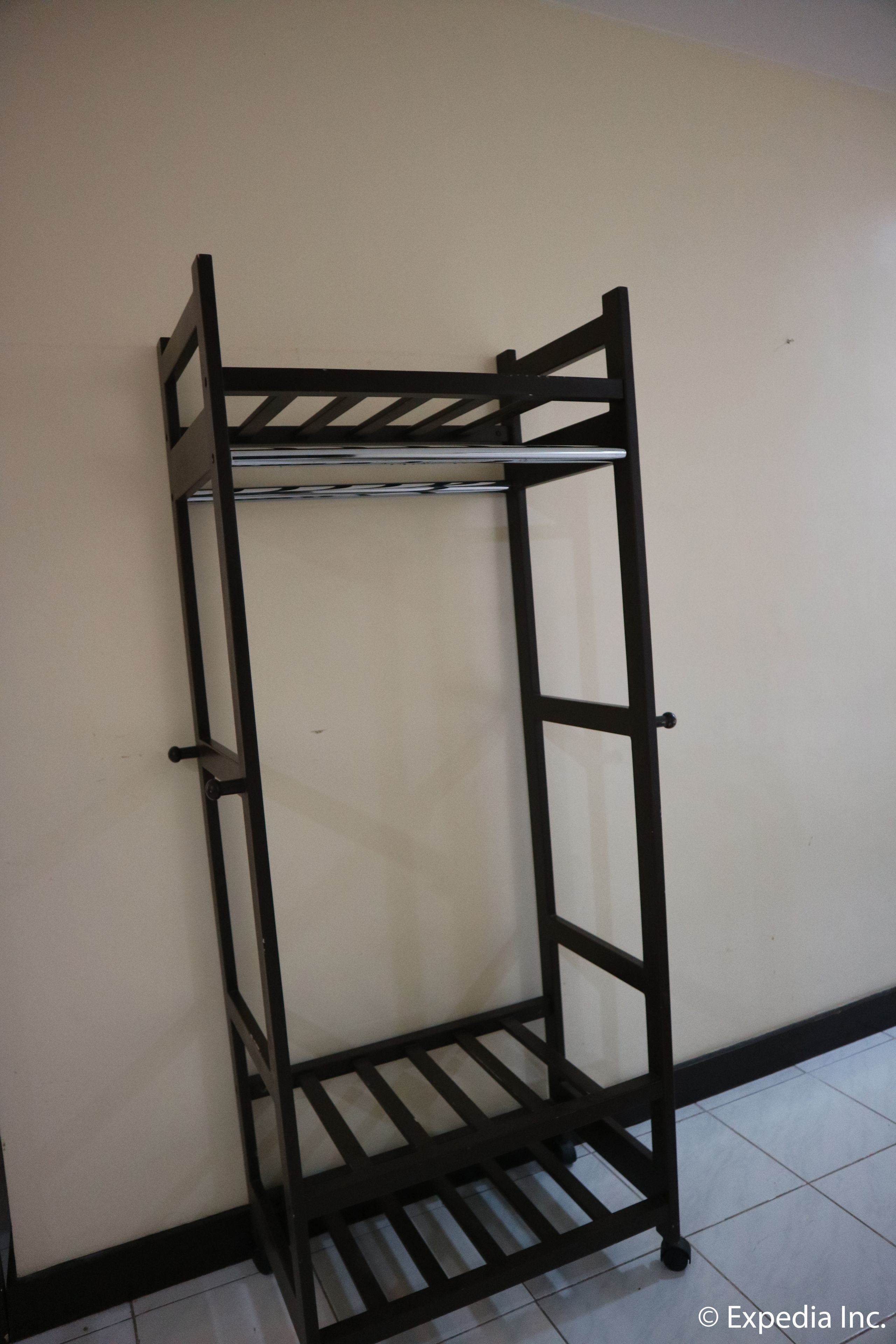 Un estante de metal negro contra una pared lisa con piso de baldosas.