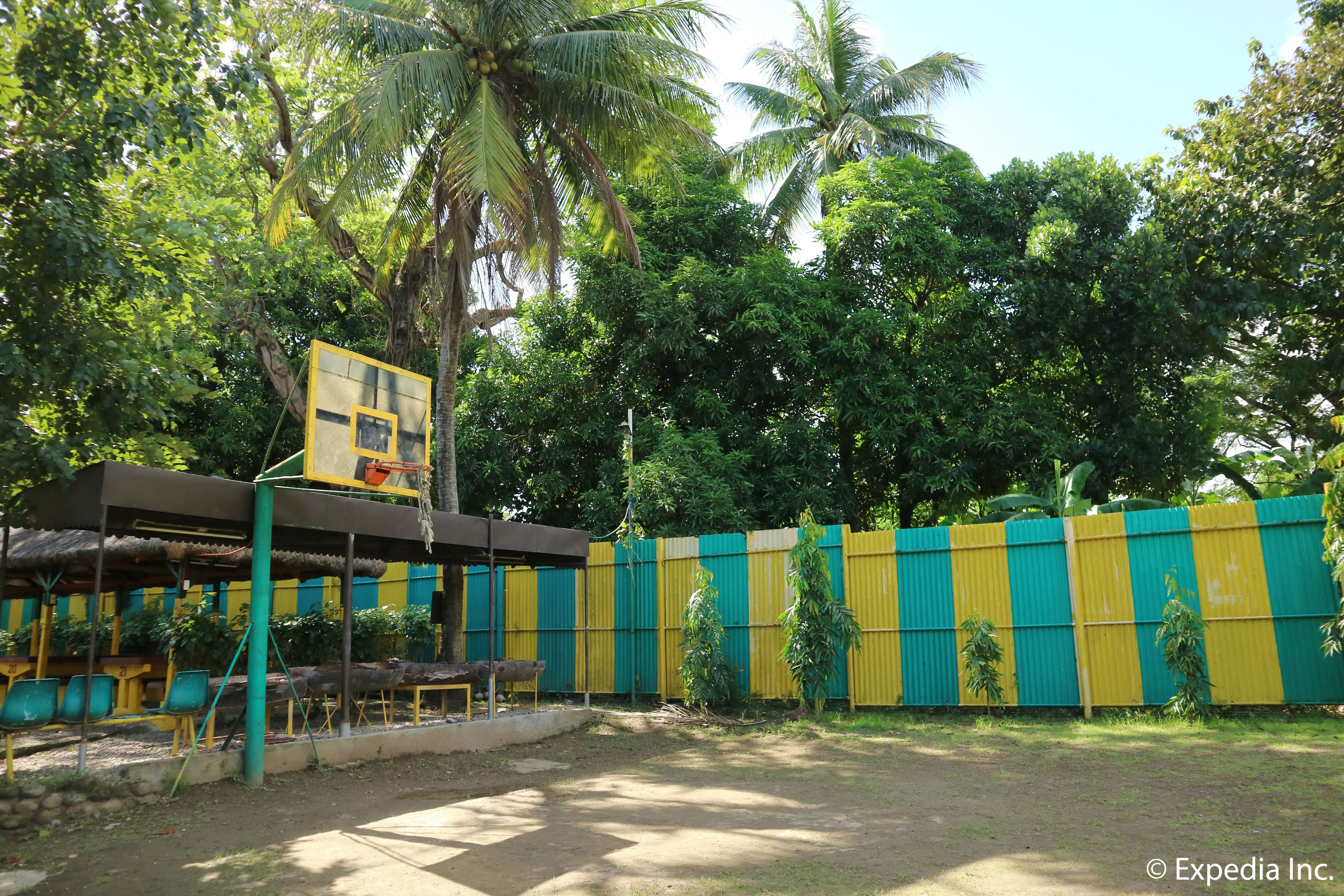 Un espacio al aire libre amurallado con cancha de baloncesto, asientos y una zona cubierta para sentarse.