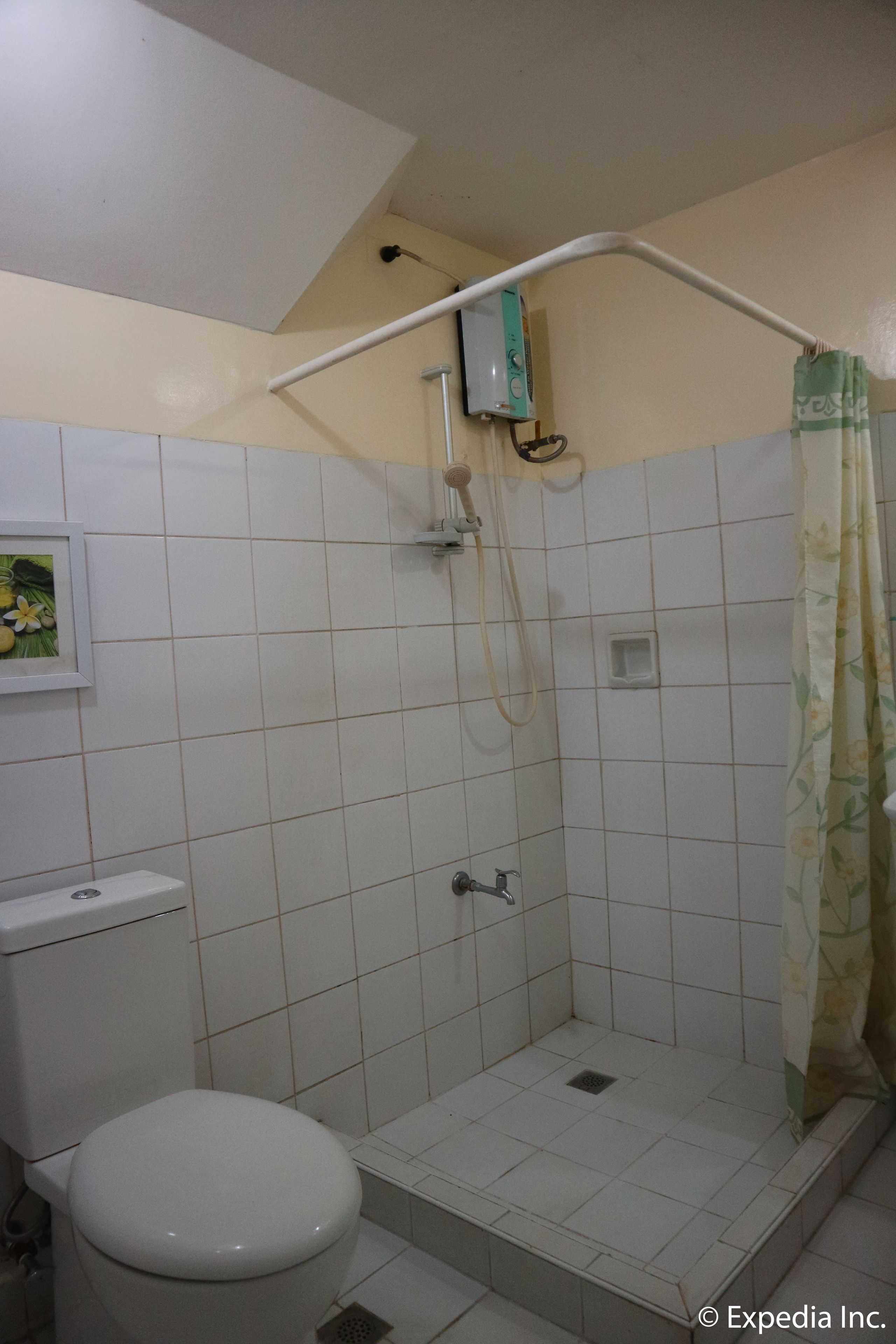 A small bathroom with a toilet, a shower stall, and a tiled floor.