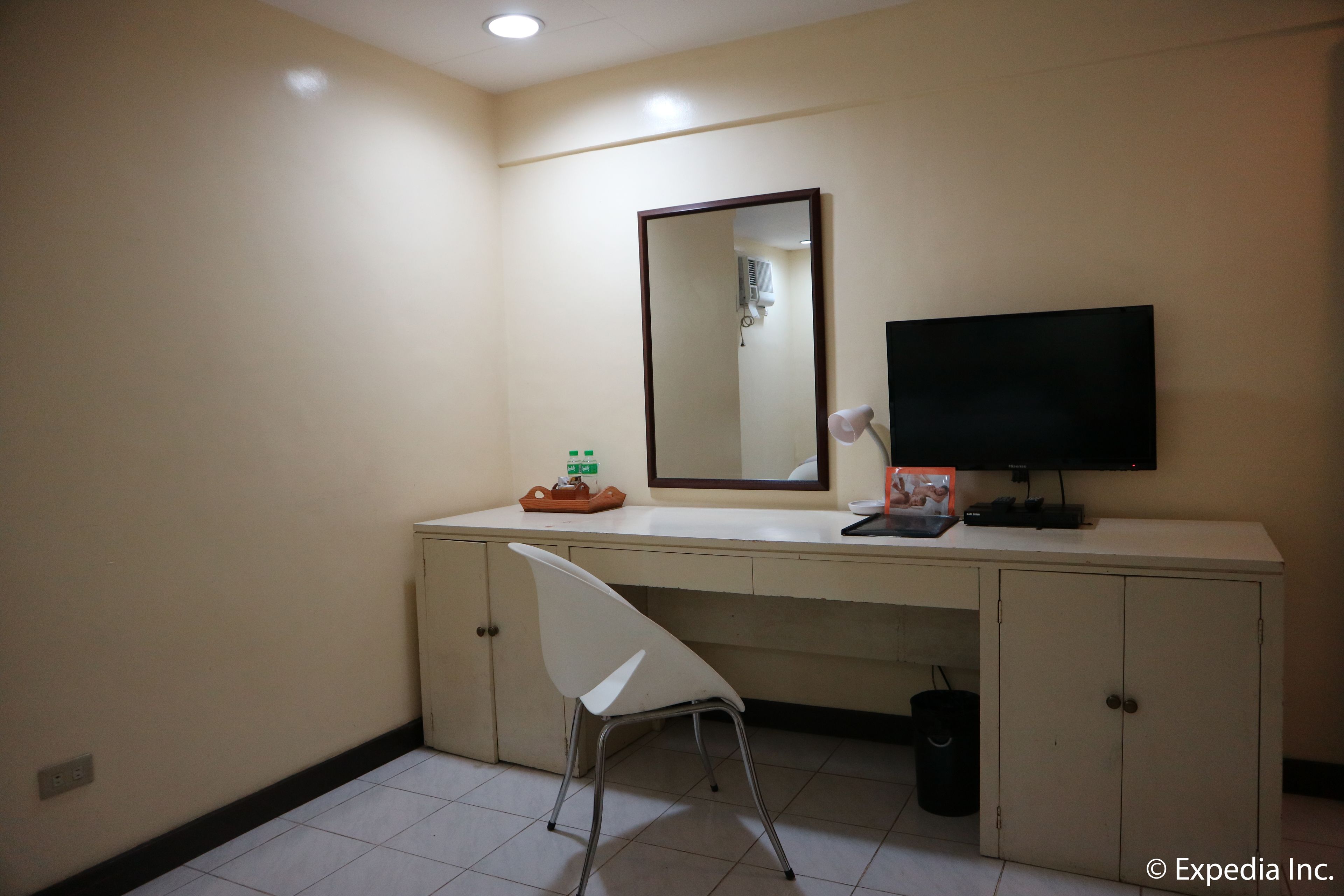 A hotel bathroom with a white sink, mirror, and a television mounted on the wall.