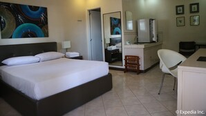 A hotel room with a large bed, a desk with a chair, a mirror, and artwork on the walls. - Riverview Resort & Conference Center (Calamba)