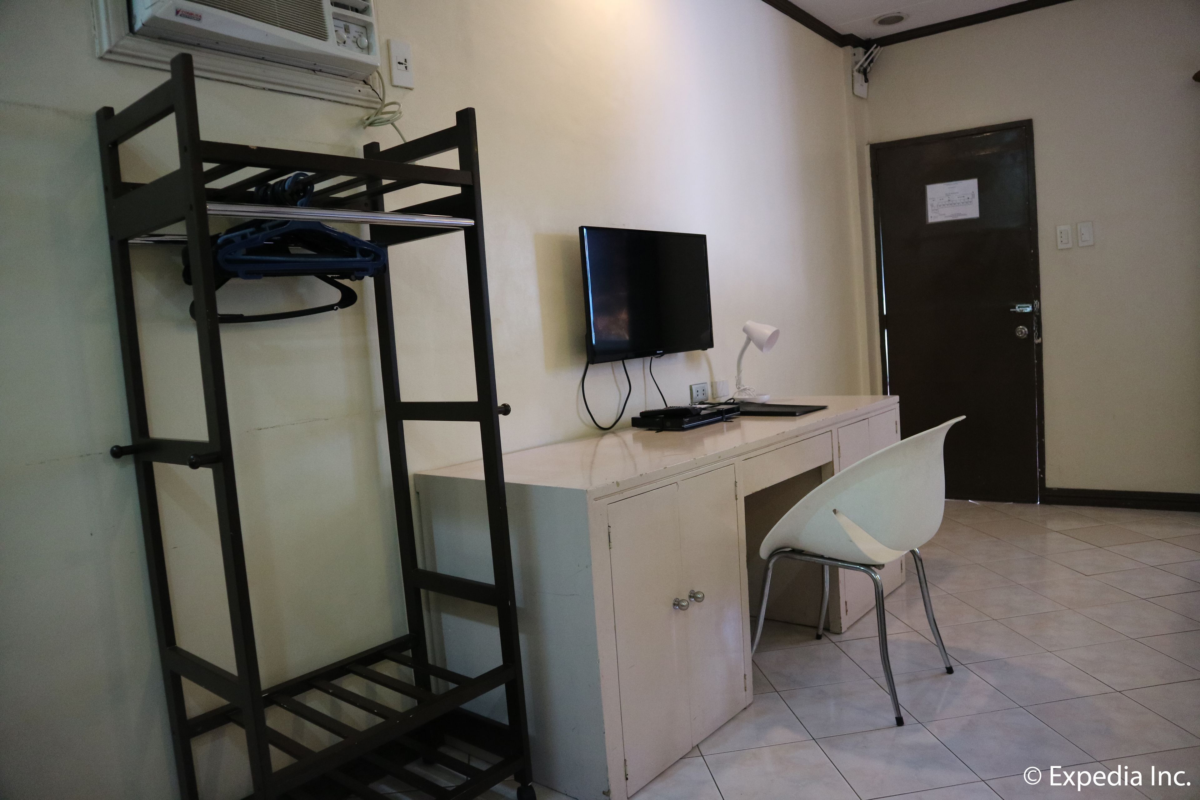 Una habitación con una cama litera, un escritorio con una computadora, una silla y un televisor.