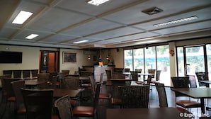 A restaurant with high ceilings, rectangular light fixtures, and large windows offering a view of the outdoors. - Riverview Resort & Conference Center (Calamba)