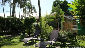 A garden with palm trees, a thatched-roof structure, and outdoor seating. - Riverview Resort & Conference Center (Calamba)
