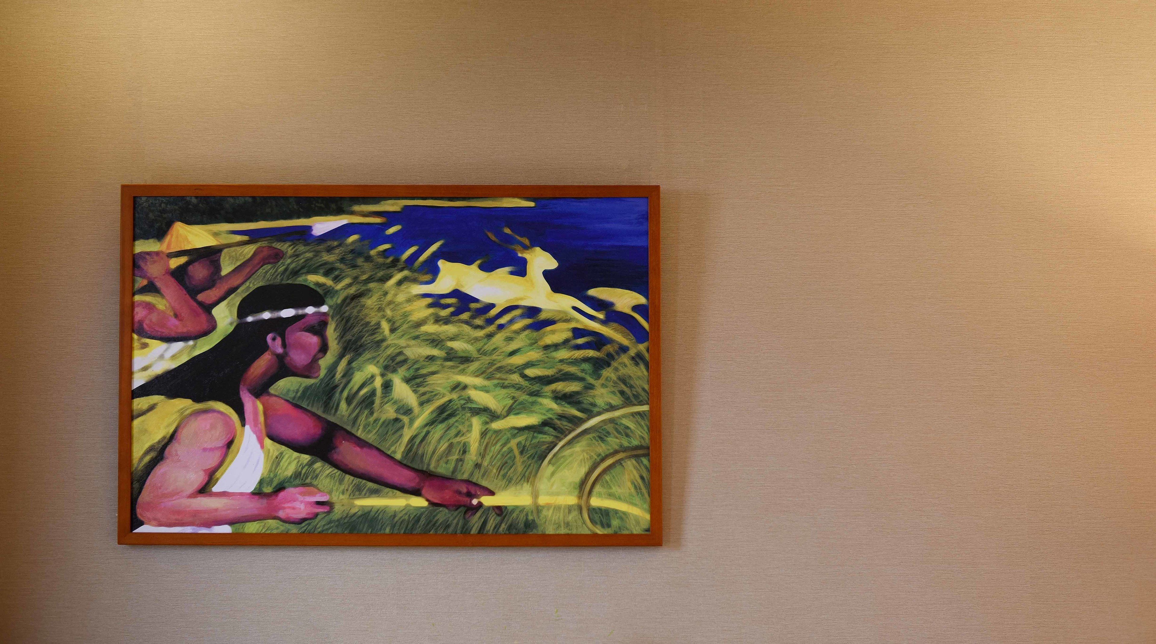 A framed painting of a woman reaching into a field of wheat.