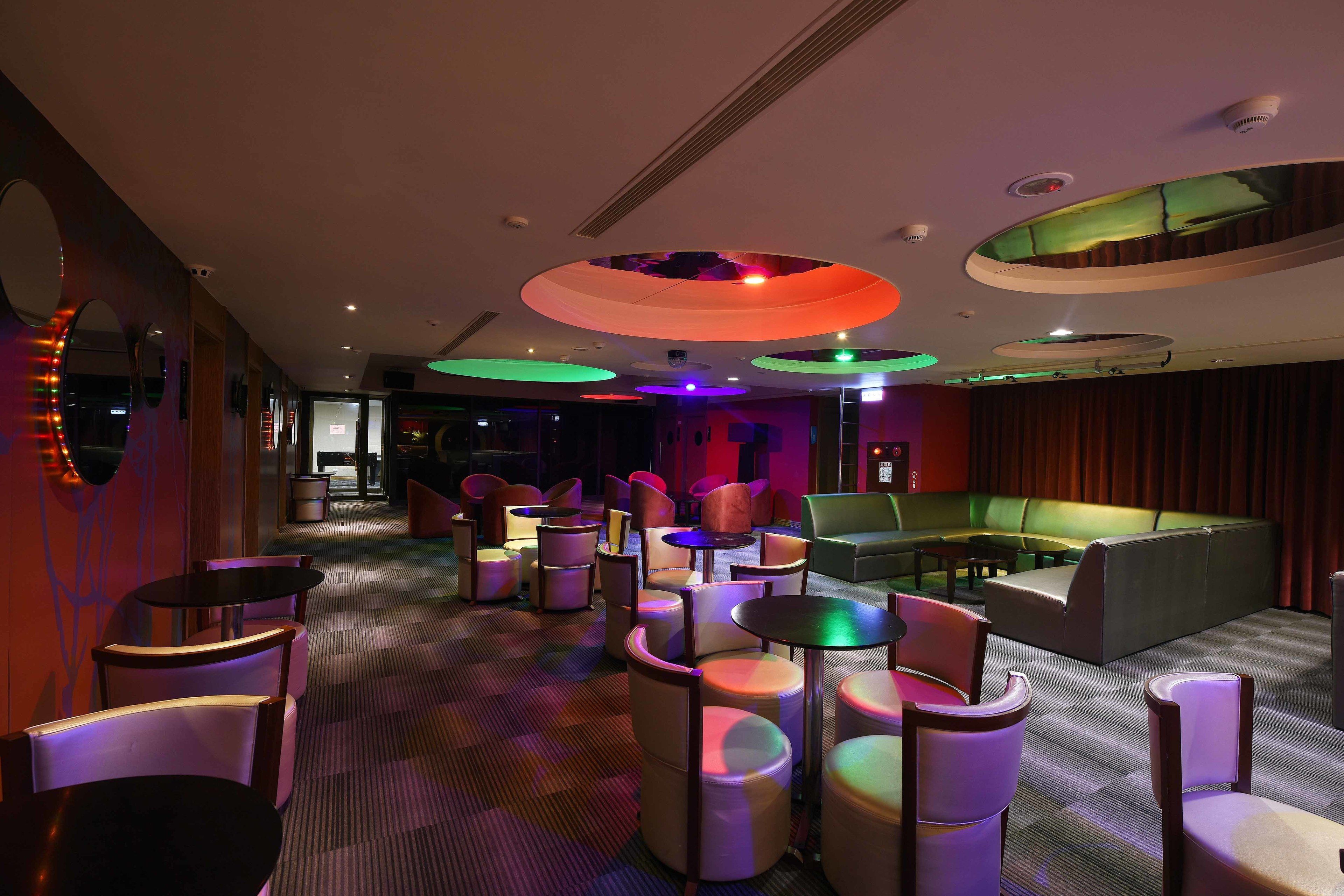 A modern lounge area with circular ceiling lights, cushioned seating, and a patterned carpet.