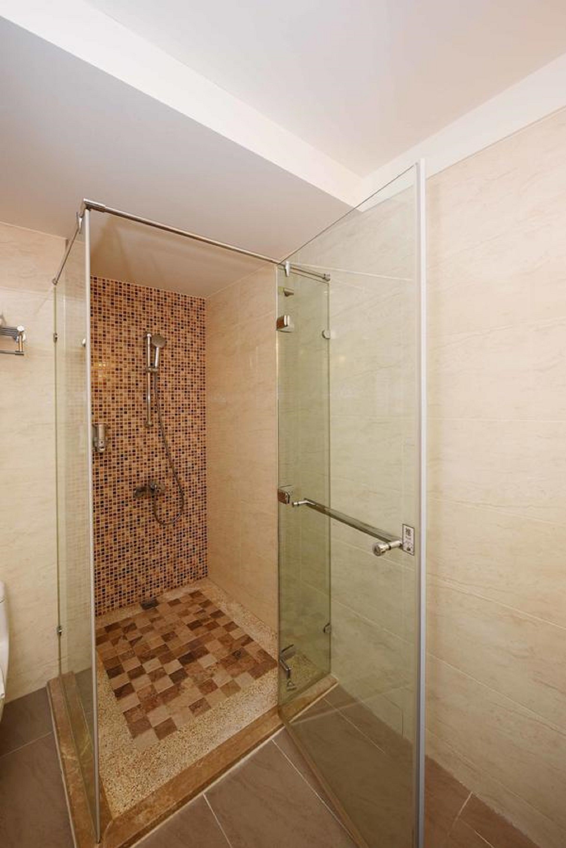 A glass-enclosed shower with a checkered floor and tiled walls.