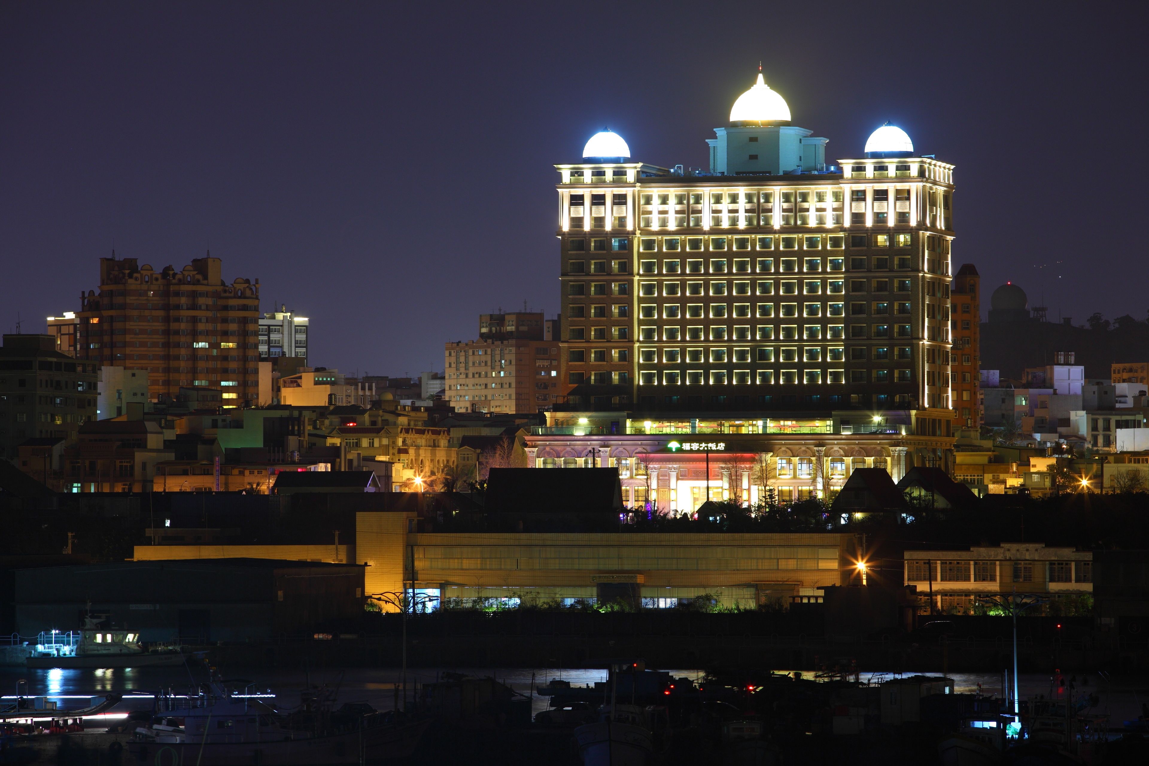 Un edificio alto con una cúpula destacada y ventanas iluminadas por la noche.