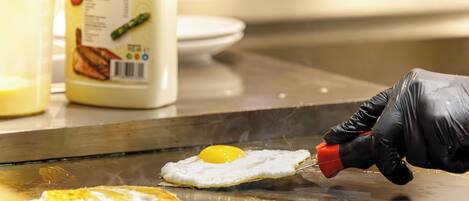 Una persona cocinando un huevo sobre una superficie caliente, usando guantes.