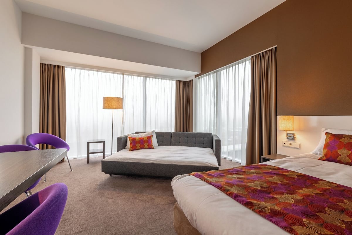A hotel room with a bed, a desk, and two chairs.