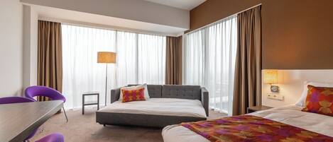 A hotel room with a bed, a desk, and two chairs.