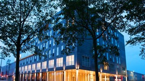 A modern hotel with a glass facade, multiple floors, and a well-lit entrance.