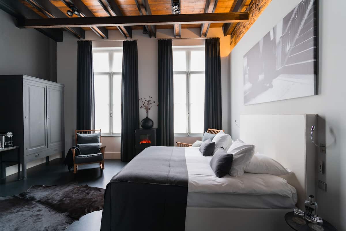 Ein modernes Hotelzimmer mit einem großen Bett, einem Holzstuhl, einem Schreibtisch und einem Kamin.
