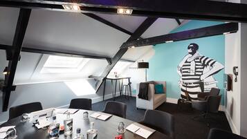 A modern meeting room with a high ceiling, skylights, and a large mural.