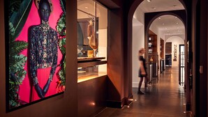 Un interior moderno con una obra de arte grande en la pared, un pasillo bien iluminado y una zona de bar visible.