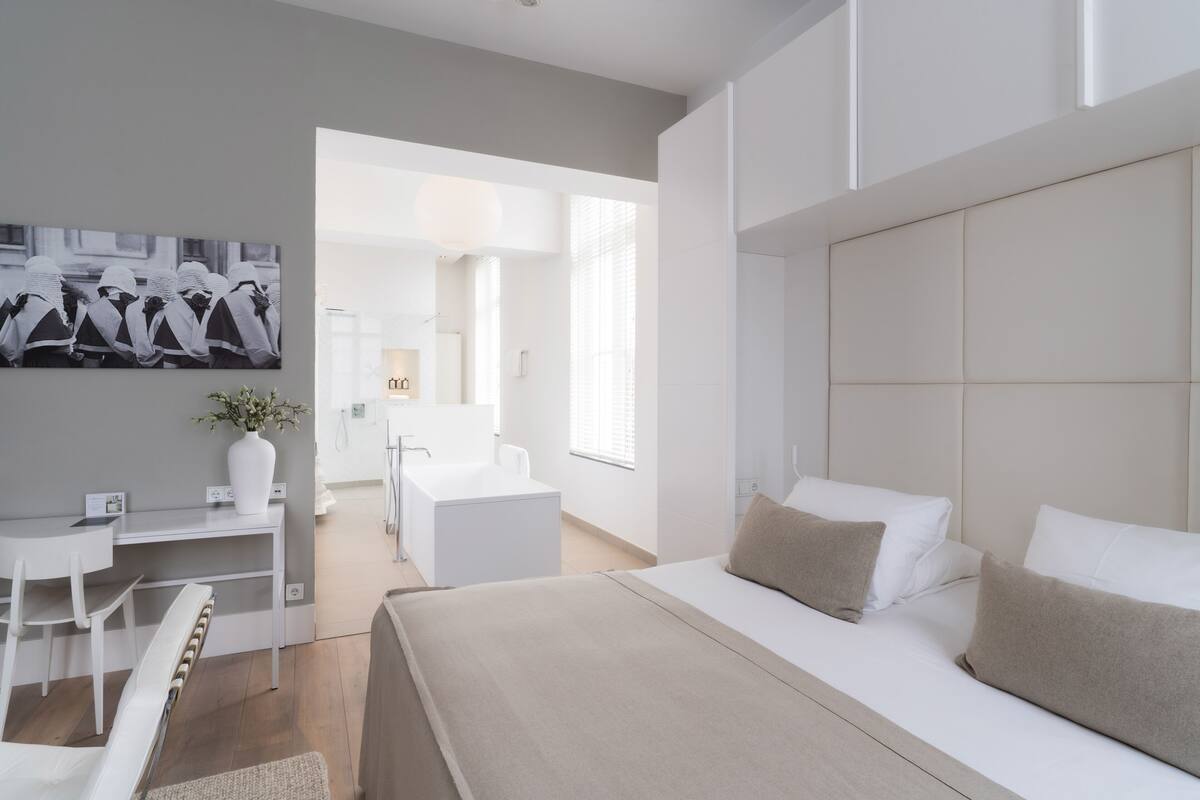 Ein modernes Hotelzimmer mit einem großen Bett, einem Schreibtisch und Blick ins Bad.