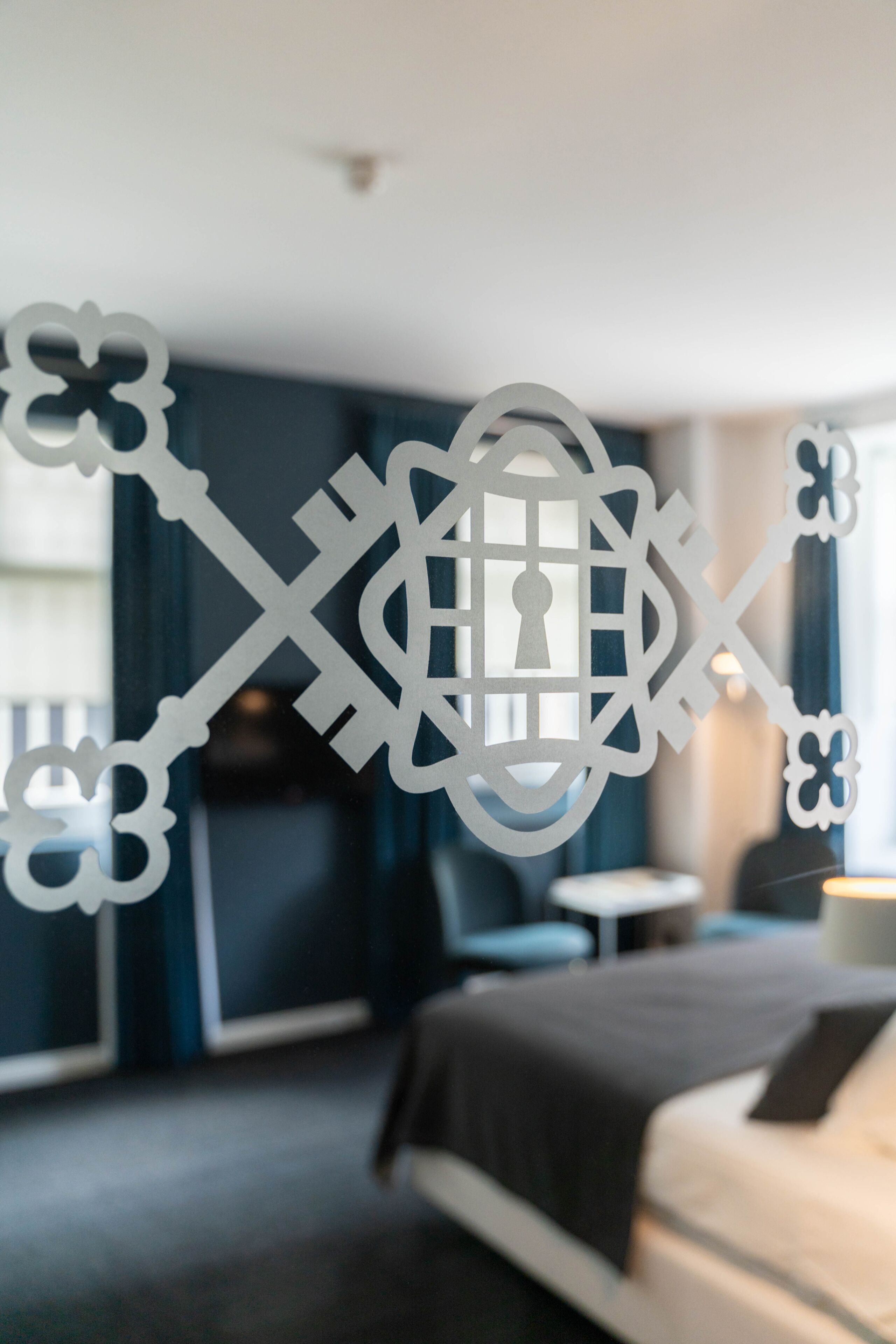 A modern hotel room with a bed, a small round table, and a decorative wall piece.