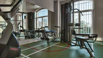 A gym with exercise equipment, large windows, and a green floor.