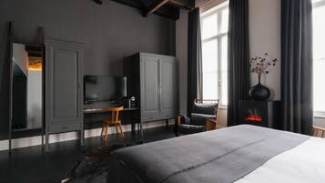 Une chambre moderne avec un grand lit, un bureau, une télévision et une cheminée.