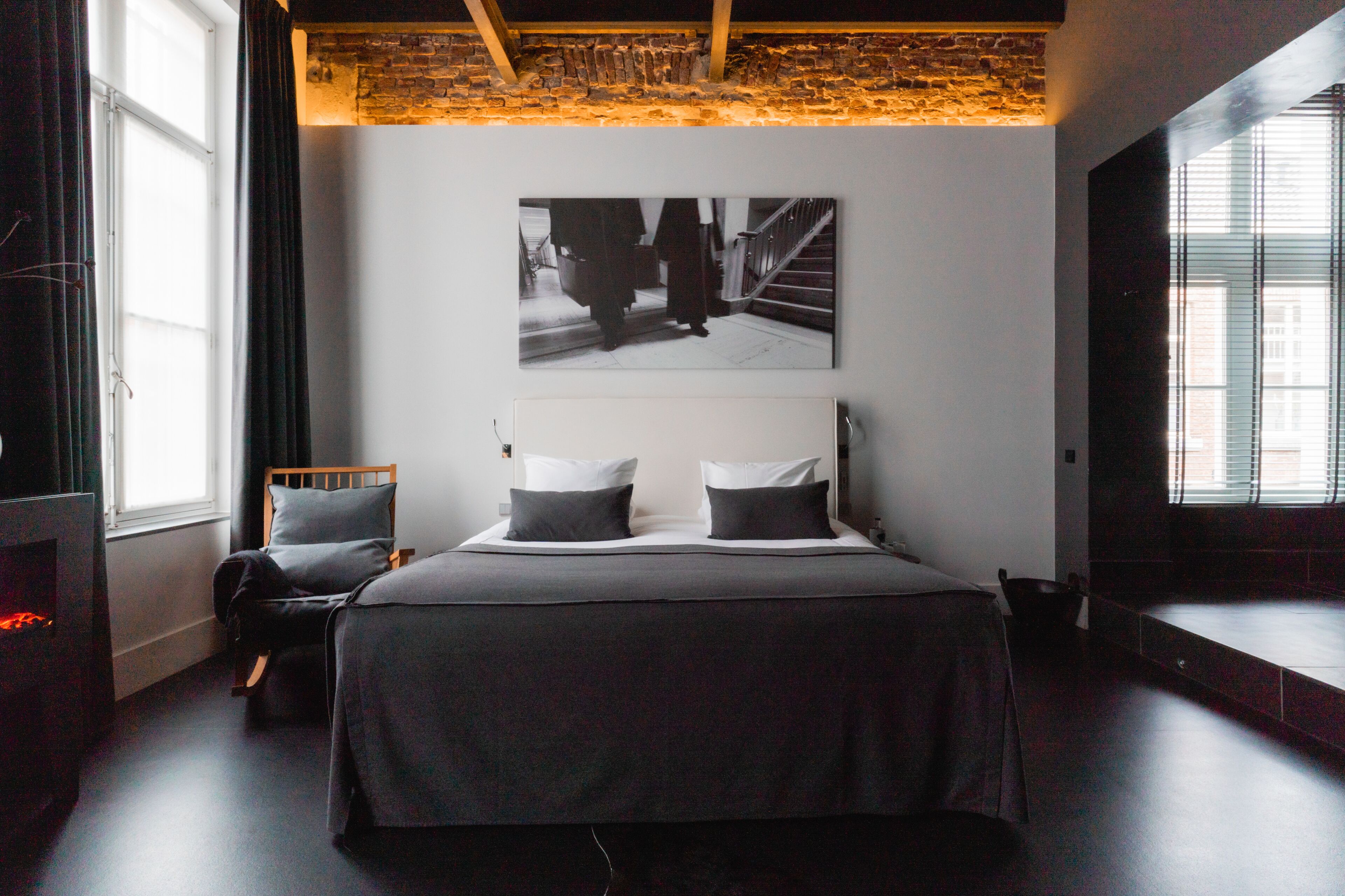 A modern bedroom with a large bed, a headboard, a wall-mounted picture, and a window with curtains.